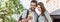 Beautiful happy young couple using smartphone outdoors panoramic banner. Joyful smiling woman and man looking at mobile phone in a