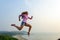 Beautiful happy young dark-haired woman jumps high and makes dynamic movements. Sporty girl in shirt, shorts and sneakers