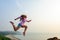 Beautiful happy young dark-haired woman jumps high and makes dynamic movements. Sporty girl in shirt, shorts and sneakers