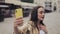 Beautiful happy young girl making a video call holding phone vertical smiling talking standing on the city street