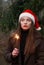 Beautiful happy young girl with Santa Claus hat. Holding sparklers