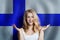 Beautiful happy young woman against the finnish flag background. Live, education and work in Finland