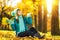 Beautiful happy young woman in the autumn park. Joyful woman wearing bright teal hat and scarf is having fun outdoors in a bright