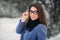 Beautiful happy young woman with black glasses wearing winter coat color Blue Cobalt and black scarf covered with snow