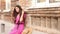 Beautiful happy young woman sits near an old building and chatting with her boyfriend or family