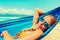 Beautiful Hawaii beach. Girl relaxing in hammock on the tropical beach