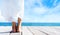 Beautiful and healthy feet of a young girl in white dress on a wooden pier. Vacation, resort and traveling concept.