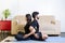 Beautiful hetero caucasian couple in black clothes on blue yogamat doing sit back-to-back pose with crossed arms