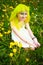 Beautiful hipster alternative young woman with yellow hair sits in grass with dandelion in park