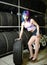 Beautiful hipster girl automobile mechanic works with tires on wheels