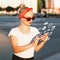 Beautiful hipster girl with sunglasses holding a phone with flying icons.