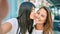 Beautiful hispanic mother and daughter smiling happy making selfie by the camera at the city