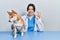 Beautiful hispanic veterinarian woman checking dog health doing ok sign with fingers, smiling friendly gesturing excellent symbol