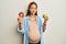 Beautiful hispanic woman expecting a baby, holding food puffing cheeks with funny face