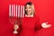 Beautiful hispanic woman holding menorah hanukkah jewish candle celebrating achievement with happy smile and winner expression