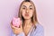 Beautiful hispanic woman holding piggy bank puffing cheeks with funny face