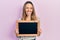 Beautiful hispanic woman holding small blackboard sticking tongue out happy with funny expression