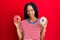 Beautiful hispanic woman holding tasty colorful doughnuts in shock face, looking skeptical and sarcastic, surprised with open