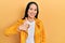 Beautiful hispanic woman with nose piercing wearing yellow leather jacket doing happy thumbs up gesture with hand