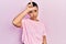 Beautiful hispanic woman with short hair wearing casual pink t shirt making fun of people with fingers on forehead doing loser