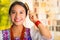 Beautiful hispanic woman wearing white blouse with colorful embroidery, using small hairbrush during makeup routine