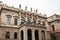 Beautiful historical building in Prague with balcony, columns and sculptures standing at the top. Czech architecture.