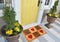 Beautiful Home sweet home peach color coir doormat with hearts Placed outside door with yellow flowers and green leaves