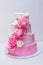 A beautiful home wedding four-tiered cake decorated with pink roses and leaves in a rustic style