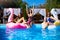 Beautiful hot pretty girls in bikini have fun in swimming pool on inflatable pink flamingo, swan floaties. Attractive