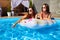 Beautiful hot pretty girls in bikini are swimming in a pool on an inflatable donut floaty. Attractive slim women in