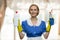 Beautiful house maid holding cleaning supplies and looking at camera.