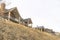 Beautiful houses sitting on top of grassy slope beneath sky filled with clouds