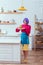 beautiful housewife in colorful clothes with purple hair holding plate with pancakes