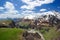 Beautiful huge mountains peaks in snow, blue sky, white clouds, blue lake at the foot of the mountain, green hills, green valley