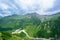 Beautiful huge mountains peaks in snow, blue sky, white clouds, blue lake at the foot of the mountain, green hills, green valley