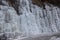 Beautiful ice structures of a frozen waterfall, pretty icicles forming an interesting pattern on a dark rock,