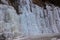 Beautiful ice structures of a frozen waterfall, pretty icicles forming an interesting pattern on a dark rock,