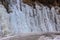 Beautiful ice structures of a frozen waterfall, pretty icicles forming an interesting pattern on a dark rock,