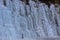 Beautiful ice structures of a frozen waterfall, pretty icicles forming an interesting pattern on a dark rock,