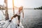 Beautiful icture of handsome and serious sailor standing on his yacht. He holds on tube and look at edge of boat. Young