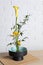 Beautiful ikebana for stylish house decor. Floral composition with fresh calla, chrysanthemum flowers and branches on wooden table