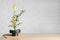 Beautiful ikebana for stylish house decor. Floral composition with fresh calla, chrysanthemum flowers and branches on wooden table