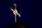 Beautiful illuminated golden cross atop a church at night time with darkened sky in background
