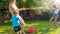 Beautiful image of happy laughing family with children having fun at hot summer day with water guns and garden hose