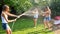 Beautiful image of happy laughing family with children having fun at hot summer day with water guns and garden hose