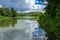 A beautiful image of landscape from the center of the river, surrounded by trees and reeds on the shore and distant horizon again