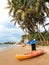 Beautiful image of plastic canoe or kayak lying under big palm tree on the ocean beach