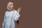 Beautiful indonesian woman wearing hijab is pointing to the right side with surprise expression