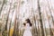 Beautiful innocent young brunette bride in gorgeous white dress with bouquet at pine wood forest
