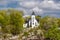 Beautiful inviting view of old vintage white church standing on a rock cliff in woods